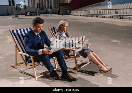 young business people working with laptop while sitting on sun loungers on parking Stock Photo