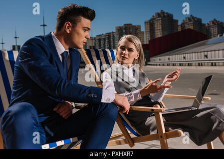 young business people working with laptop while sitting on sun loungers on parking Stock Photo