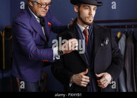 Tailor with client in atelier. Sewing custom made suit Stock Photo