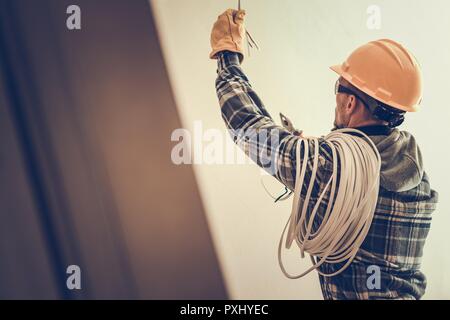 Electrician in Yellow Hard Hat with Cable Working in the Construction Area. Stock Photo