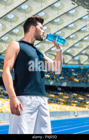 handsome young man drinking water after training at sports stadium Stock Photo