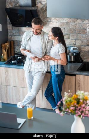 married couple using digital tablet together in kitchen, smart home concept Stock Photo