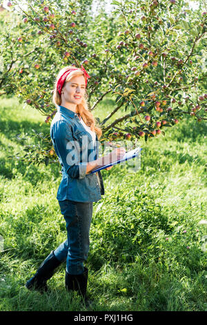 attractive farmer examining harvest in apple garden at farm Stock Photo