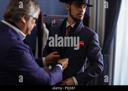 Tailor with client in atelier. Sewing custom made suit Stock Photo