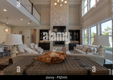 Living room in a home with windows couch chairs fireplace chandelier and television Stock Photo