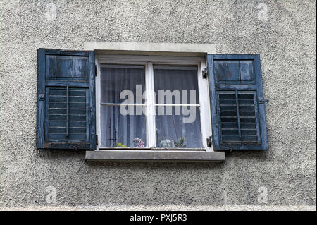 European window with weathered wooden shutters on gray stone wall exterior Stock Photo