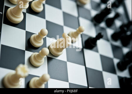 Close-up of black chess pieces on a black and white chessboard with selective focus and shallow depth of field. Stock Photo
