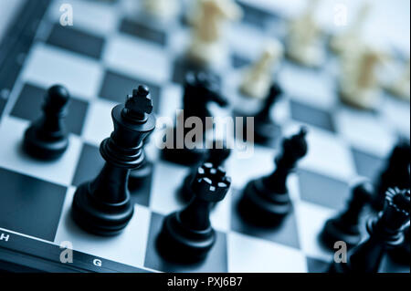 Close-up of black chess pieces on a black and white chessboard with selective focus and shallow depth of field. Stock Photo