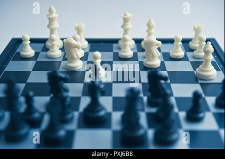 Close-up of black chess pieces on a black and white chessboard with selective focus and shallow depth of field. Stock Photo