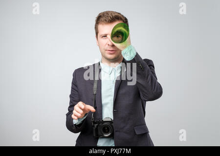 Handsome young man holding a photo camera. Studio shoot. Stock Photo