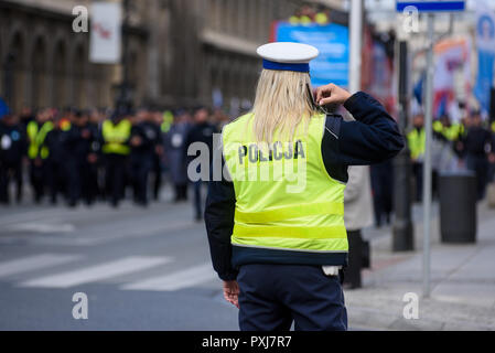 Police woman standing on the cross road and controlling the traffic. Dressed in a police uniform with yellow west. Stock Photo