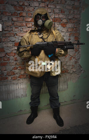 Stalker in gas mask with weapon near the brick wall background Stock Photo