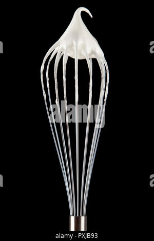 Beaten egg whites on a whisk, isolated on black background Stock Photo