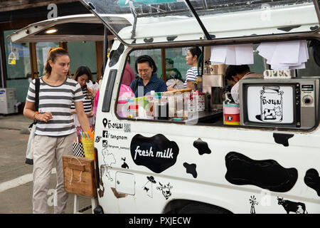 Tourist buys coffee at mobile coffee shop at JingJai Farmer's Market, Chiang Mai, Thailand Stock Photo