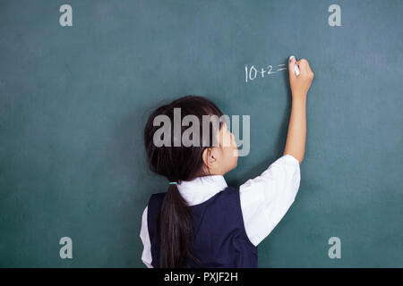 Asian Chinese little girl writing on blackboard in the classroom Stock Photo