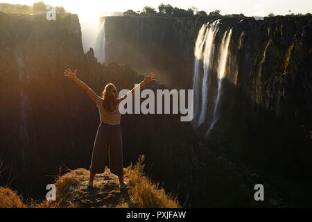 Woman standing in front of Victoria Falls near Livingstone, Zambia Stock Photo