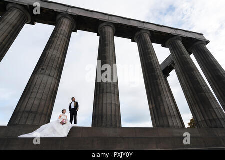 Edinburgh, Scotland, UK. 23 October, 2018. Chinese couple in formal wear pose for pre-wedding photographs on the National Monument of Scotland on Calton Hill in Edinburgh, Scotland, UK. Credit: Iain Masterton/Alamy Live News Stock Photo