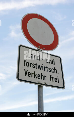 A road sign that says - No thoroughfare - except agricultural and silvicultural traffic in german language in front of blue sky.