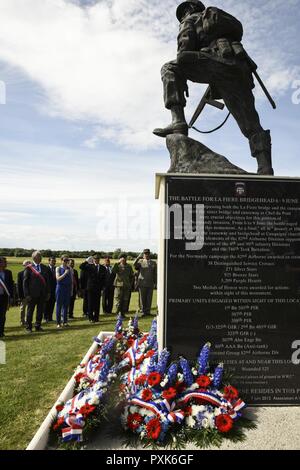 U.S., German and French dignitaries salute as ‘Taps’ is played, June 4, 2017, during the ‘Iron Mike’ wreath-laying ceremony in Sainte-Mere-Eglise, France. This ceremony commemorates the 73rd anniversary of D-Day, the largest multi-national amphibious landing and operational military airdrop in history, and highlights the U.S.’ steadfast commitment to European allies and partners. Overall, approximately 400 U.S. servicemembers from units in Europe and the U.S. are participating in ceremonial D-Day events from May 31 to June 7, 2017. Stock Photo