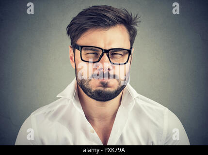 Portrait of bearded man in glasses and white shirt looking super annoyed and negatively at camera Stock Photo