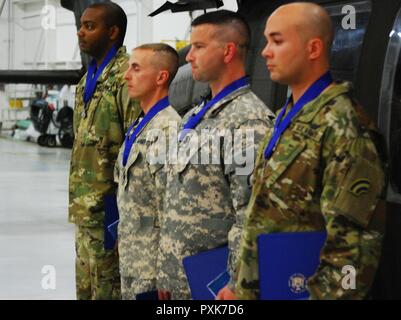 Four New York Army National Guard Soldiers who received New York's highest medal for heroism, the Medal for Valor, stand in formation during award ceremonies on Sunday, June 4, 2017 at Army Aviation Support Facility # 1 in Ronkonkoma, N.Y. The men were recognized for rescuing the pilot of a light plane which crashed in flames on Feb. 26. They are, from left, Sgt. Yaanique Scott, Warrant Officer Christopher Hansen, Chief Warrant Officer 2 Aaron Pacholk and Chief Warrant Officer 2 Ronald Ramirez. Stock Photo