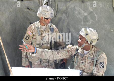 Command Sgt. Maj. Jon A. Martin, an observer controller at the National Training Center, speaks with Spc. Cory Robinson, assigned to Headquarters Company, 150th Engineer Battalion, Mississippi Army National Guard, about his training experience during his rotation, June 2, 2017, at the National Training Center. (Mississippi Stock Photo