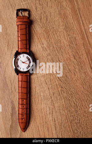 Luxurious brown leather watch with white round dial in wooden box Stock Photo