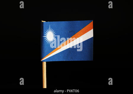 A official flag of marshall islands on wooden stick on black background. Marshall islands are located in pacific ocean and belongs to oceania. Sun on  Stock Photo