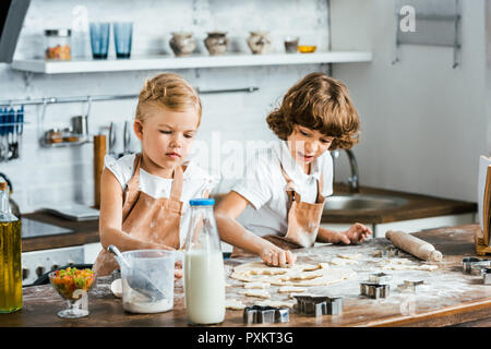 adorable children in aprons preparing dough for tasty cookies Stock Photo