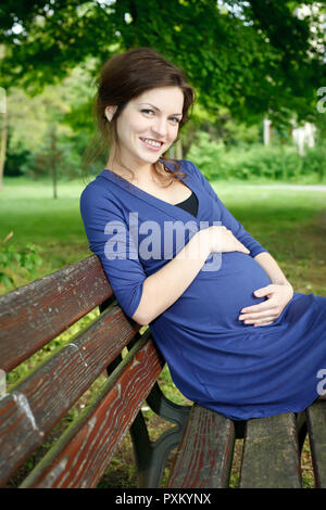 Beautiful pregnant woman sitting on bench Stock Photo