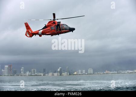 Petty Officer 3rd Class Bryan Evans, a Coast Guard Air Station Miami rescue swimmer, prepares for a free fall deployment from a MH-65 Dolphin helicopter east of Miami Beach on June 6, 2017. (Coast Guard