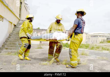 Fire officers from the Bridgetown Fire Department assess and assist a volunteer actor during a mass casualty drill at the site of the former Glendairy Prison. The scenario was based on the idea that an earthquake caused a hotel to collapse and local emergency services and Barbados Defence Force (BDF) personnel were working together to rescue and treat survivors. Tradewinds 2017 Regional Observer and Assessment Team (ROAT) members from multiple countries watched the exercise to take notes and create an assessment for Barbadian officials. The report will contain ideas of ways emergency services  Stock Photo