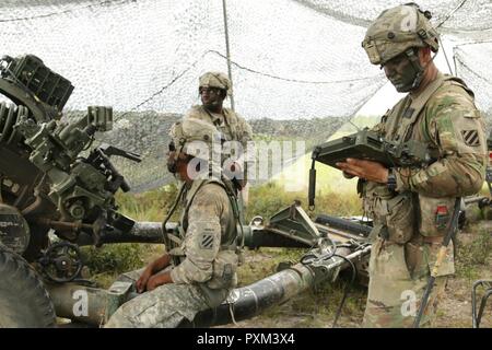 Staff Sgt. Cameron Holmes (right), a team chief from Company F, Task Force 1st battalion, 28th Infantry Regiment, reads a firing mission to his soldiers on June 12, 2017 at Fort Stewart, Ga. Task Force 1-28 is an active duty component partnering with 1st Battalion, 128th Field Artillery Regiment, 48th Infantry Brigade Combat Team as part of the Associated Units Pilot Program. Stock Photo