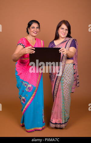 Two mature Indian women holding laptop computer Stock Photo