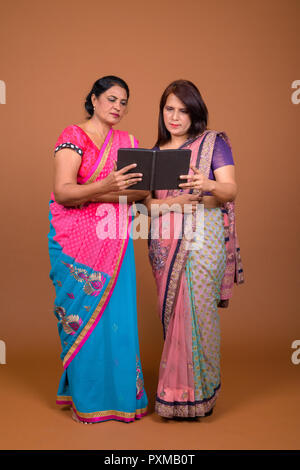 Two mature Indian women reading book together Stock Photo