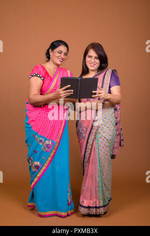 Two mature Indian women reading book together Stock Photo