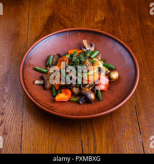 A meal of stewed mushrooms, peppers, tomatoes and onions on a plate Stock Photo