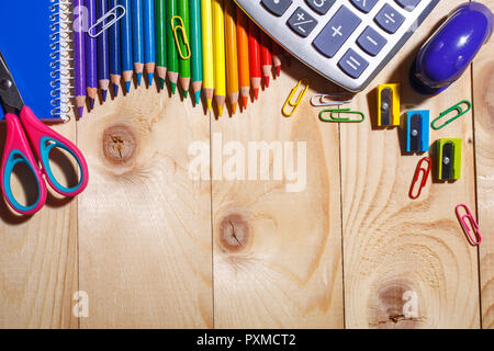 Pencils in rainbow color wave and other stuff lying on a light wooden background. 1 September concept postcard, teachers day. Top view, flat lay. copy Stock Photo