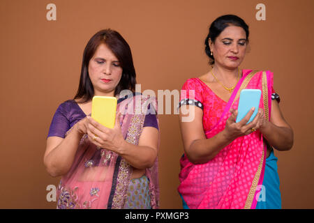 Two mature Indian woman using mobile phone Stock Photo