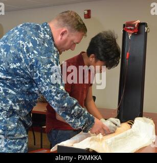 JACKSONVILLE, Fla. (June 13, 2017) – Hospital Corpsman 2nd Class Adam Petree, of Naval Hospital Jacksonville’s Staff Education and Training, instructs Christian Corpus, a Darnell-Cookman School of the Medical Arts student, on starting intravenous fluids on a simulated patient. Eleven high school students are participating in the hospital’s Science, Service, Medicine and Mentoring (S2M2) summer internship. The goal of S2M2 is to nurture the next generation of health care professionals. Stock Photo