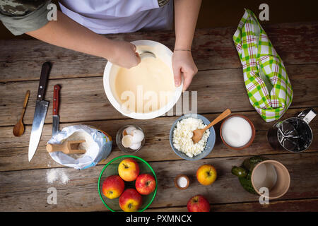 Top view of the dough and ingredients for making traditional thin pancakes. The process of cooking pancakes for breakfast. Hands girls whisking dough. Stock Photo
