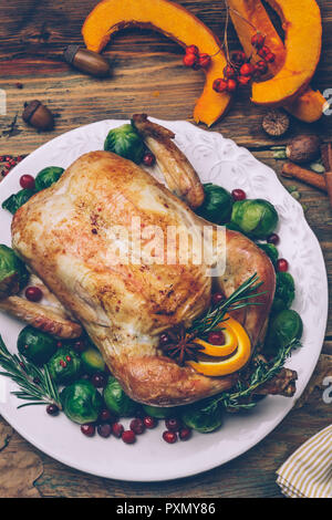 Thanksgiving roasted chicken with Brussels sprouts and spices on a rustic wooden table. Thanksgiving dinner or fall dinner concept background with aut Stock Photo