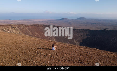 girl sitting on the top of a volcano, fuerteventura Stock Photo