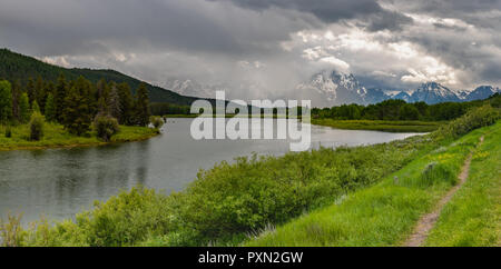 Thin Dirt Trail Along Heron Lake with Tetons in Distance Stock Photo