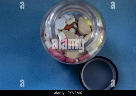 different pills in a bottle on blue background Stock Photo