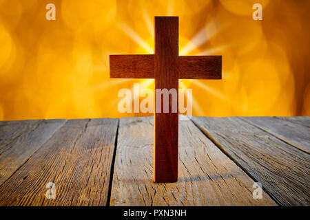 Christian wood cross on blur flare lights and wooden background Stock Photo