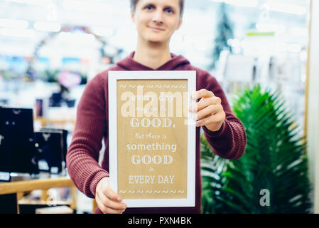 Portrait of Young smiling caucasian man holding motivational message typing on the wooden board. Everyday Inspirational quotes concept. Vintage styled Stock Photo