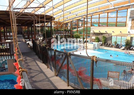 Liptovsky Mikulas, Slovakia - May 04, 2014: Suspension bridge over the blue pool with thermal water in the aquapark in Liptovsky Mikulas, Slovakia. Stock Photo