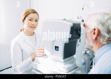Smiling optometrist while working while working. Eye exam of the elderly people Stock Photo