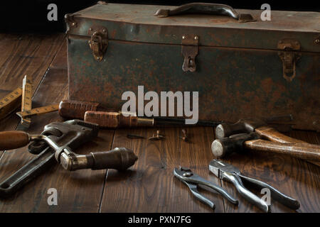 Antique tools and grungy toolbox on dark wood surface Stock Photo